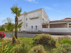 un bâtiment blanc avec un palmier devant dans l'établissement 400m de la Grande plage, 2 adultes 2 enfants, à Saint-Gilles-Croix-de-Vie
