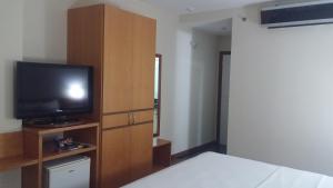 a bedroom with a bed and a television on a wooden cabinet at Vitoria Praia Hotel in Vitória