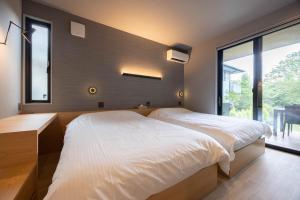 una camera da letto con due letti e una grande finestra di Toraihaku Karuizawa Hinata - Vacation STAY 87241v a Oiwake