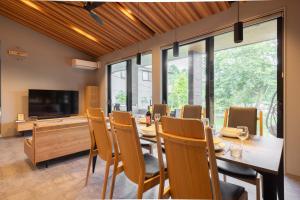 una sala da pranzo con tavolo, sedie e televisione di Toraihaku Karuizawa Hinata - Vacation STAY 87241v a Oiwake