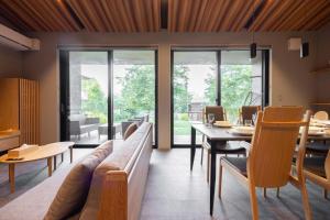 un soggiorno con un divano, un tavolo e delle sedie di Toraihaku Karuizawa Hinata - Vacation STAY 87241v a Oiwake