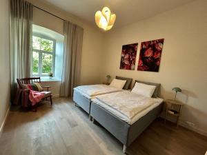 a bedroom with a bed and a chair and a window at Kalnamuiža Apartments in Smiltene