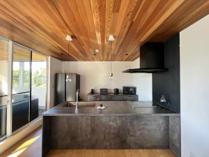 a kitchen with a concrete counter top and wooden ceilings at Cliffside Villa NIRVANA - Vacation STAY 98988v in Yakushima +18 photos