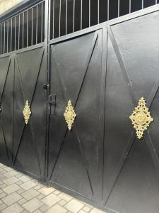 una porta da garage nera con decorazioni dorate di Charming Private House Pekini av a Tbilisi City
