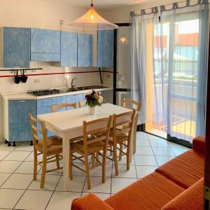 a kitchen with a table and chairs and a kitchen with blue cabinets at Tamerici in Cavallino-Treporti