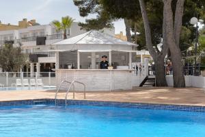 a man standing at a bar next to a swimming pool at Apartamentos Vibra Riviera in San Antonio Bay