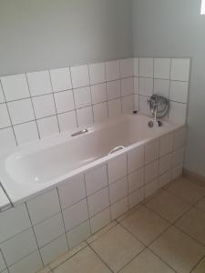 a bath tub in a bathroom with white tiles at Shalom Villa Guesthouse Walvis in Walvis Bay +11 photos
