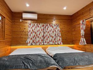 two beds in a wooden room with a window at HARUNA VILLA - Vacation STAY 27961v in Kita-karuizawa