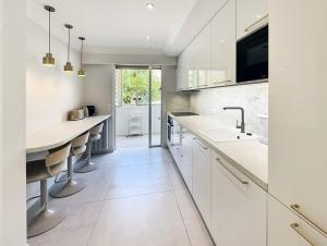 a kitchen with white cabinets and a sink and a counter at Elegant 2 Br with parking in Cannes
