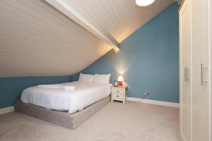 Un dormitorio con una cama blanca y una pared azul. en Perfect Bridgend Stay: Comfort & Space!, en Bridgend