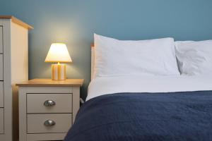 Un dormitorio con una cama y una lámpara en una mesita de noche. en Perfect Bridgend Stay: Comfort & Space!, en Bridgend 74 fotos más