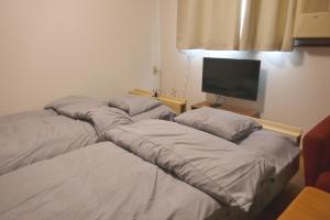 two beds in a room with a flat screen tv at Minpaku =SAKURA= - Vacation STAY 16462 in Osaka