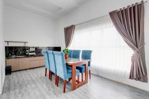 a dining room with a wooden table and blue chairs at Capital O 94740 Sudirto Villa Dan Homestay Dieng in Batur