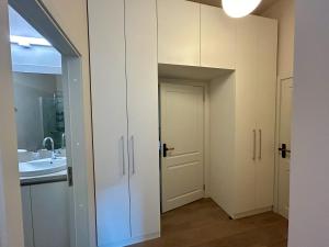 a bathroom with white cabinets and a sink at Kalnamuiža Apartments in Smiltene