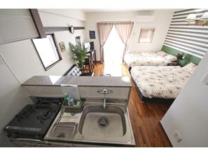 a kitchen with a stove and a sink in a room at Chura Gahna House Tsubogawa - Vacation STAY 40160v in Naha