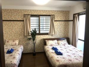 a bedroom with two beds with blue slippers on them at KY Apartment - Vacation STAY 40189v in Naha