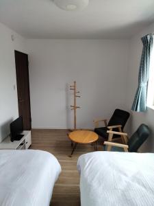 水戸市にあるGuesthouse Senba - Vacation STAY 16651のベッド2台とテーブルと椅子のある部屋
