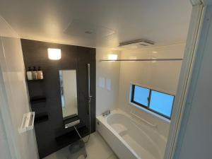 a bathroom with a tub and a sink and a mirror at emma green - Vacation STAY 55704v in Sesoko +34 photos