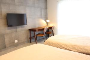 a bedroom with a desk and a television on a wall at emma green - Vacation STAY 55704v in Sesoko