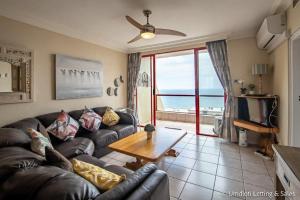 a living room with a leather couch and a table at C302 SURFSIDE in Umdloti