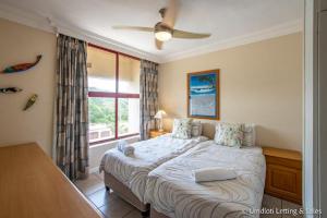 a bedroom with a bed with a ceiling fan and a window at C302 SURFSIDE in Umdloti +15 photos