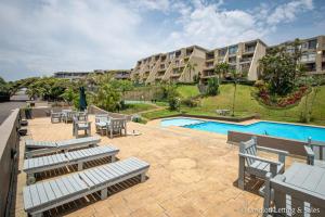a resort with a pool and chairs and a building at C302 SURFSIDE in Umdloti