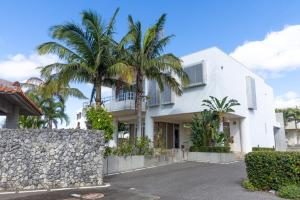 a white house with palm trees in front of it at Andiamo Nosoko - Vacation STAY 73186v in Ibaruma