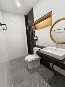 a bathroom with a sink and a toilet and a mirror at ตัง โฮเทล in Ban Rai Som