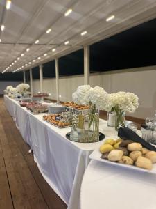 Una larga mesa blanca con pasteles y postres sobre ella. en Neas Resort, en Castel Volturno 42 fotos más