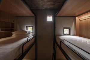 a small room with a bed and two windows at 德旅店 Dehostel in Pingtung City
