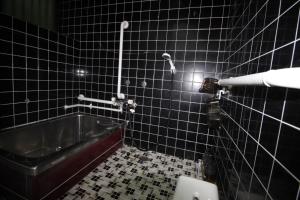 a black tiled bathroom with a tub and a toilet at Fukutokukashiya - Vacation STAY 16907 in Kagoshima +7 photos