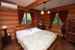 Un dormitorio con una cama en una habitación con paredes de madera. en Nasu handmade log house - Vacation STAY 16930, en Nasu-yumoto