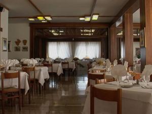 a restaurant with tables and chairs with white tablecloths at Hotel Dante in Ponte nellʼAlpi