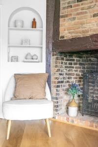 a living room with a brick fireplace and a white chair at Dolphin Cottage in Henley on Thames