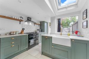 a kitchen with green cabinets and a sink at Dolphin Cottage in Henley on Thames +21 photos