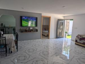 a living room with a table and a television on the wall at Guesthouse Skhirat in Skhirat