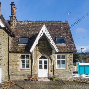 een oud stenen huis met een witte deur bij Station Cottage in Bucknell