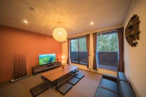 a living room with a couch and a table and a tv at Drops of Yufu -Morning Mist, Evening Calm, Dawn- - Vacation STAY 01501v in Yufuin