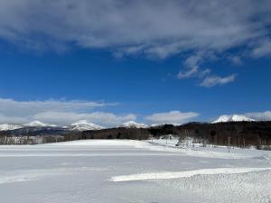 ein schneebedecktes Feld mit Bergen im Hintergrund in der Unterkunft Hinode Land - Vacation STAY 06589v in Kombu + 1 Foto