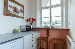 een keuken met een aanrecht met een magnetron en 2 krukken bij Station Cottage in Bucknell +13 foto's