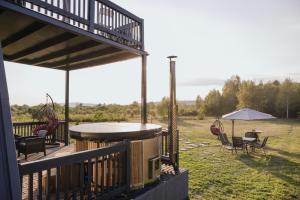 a deck with a grill and chairs and an umbrella at Cabana Ross-A in Poenari