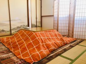 a bed with an orange comforter in a room with windows at Green House 201 - Vacation STAY 28288v in Tokyo