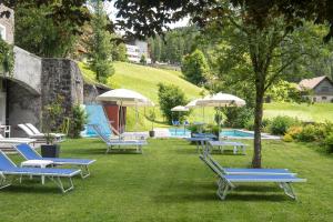 a group of lounge chairs and umbrellas on the grass at Hotel Tre Cime Sesto - Sexten in Sesto