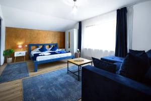 a bedroom with a blue bed and a blue couch at Residence by DANIA & PETRU in Târgu Ocna