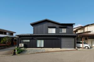 a black house with a garage on a street at villa-rizo midorigaoka - Vacation STAY 17519 in Takayama