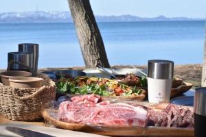 a table with a plate of meat and salad and the ocean at Roots Inawashiro Lake Area - Vacation STAY 86614v in Sekiwaki