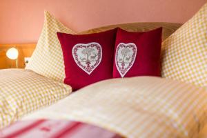 a bed with two red pillows with hearts on them at Appartement SONNENGLÜCK by MoniCare in Leutasch +15 photos