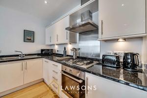a kitchen with white cabinets and a stove top oven at Town Centre Living by Lawsons with free parking in Windsor