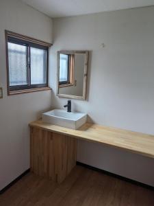 ein Badezimmer mit einem weißen Waschbecken und einem Spiegel in der Unterkunft HANARE STAY&SPACE - Vacation STAY 38426v in Misaki