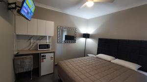 a bedroom with a bed and a tv on the wall at Cooee Motel in Gilgandra